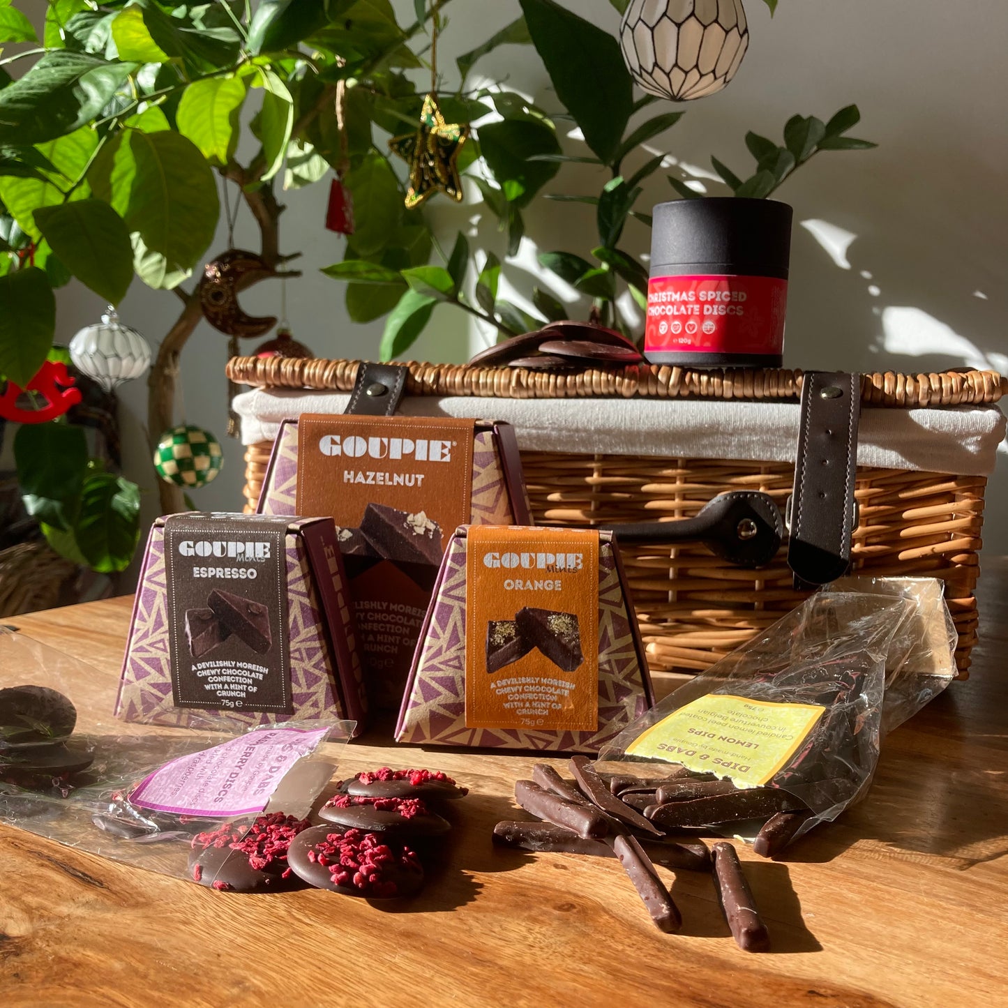 Goupie vegan chocolate products on a wooden table with plants in the background