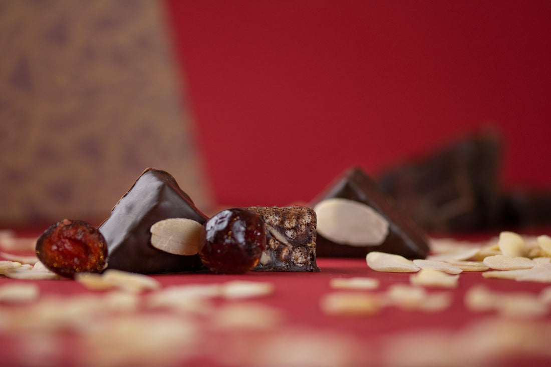 An image of Cherry & Almond chocolate Goupie with a bold red background and flaked almonds scattered in the foreground