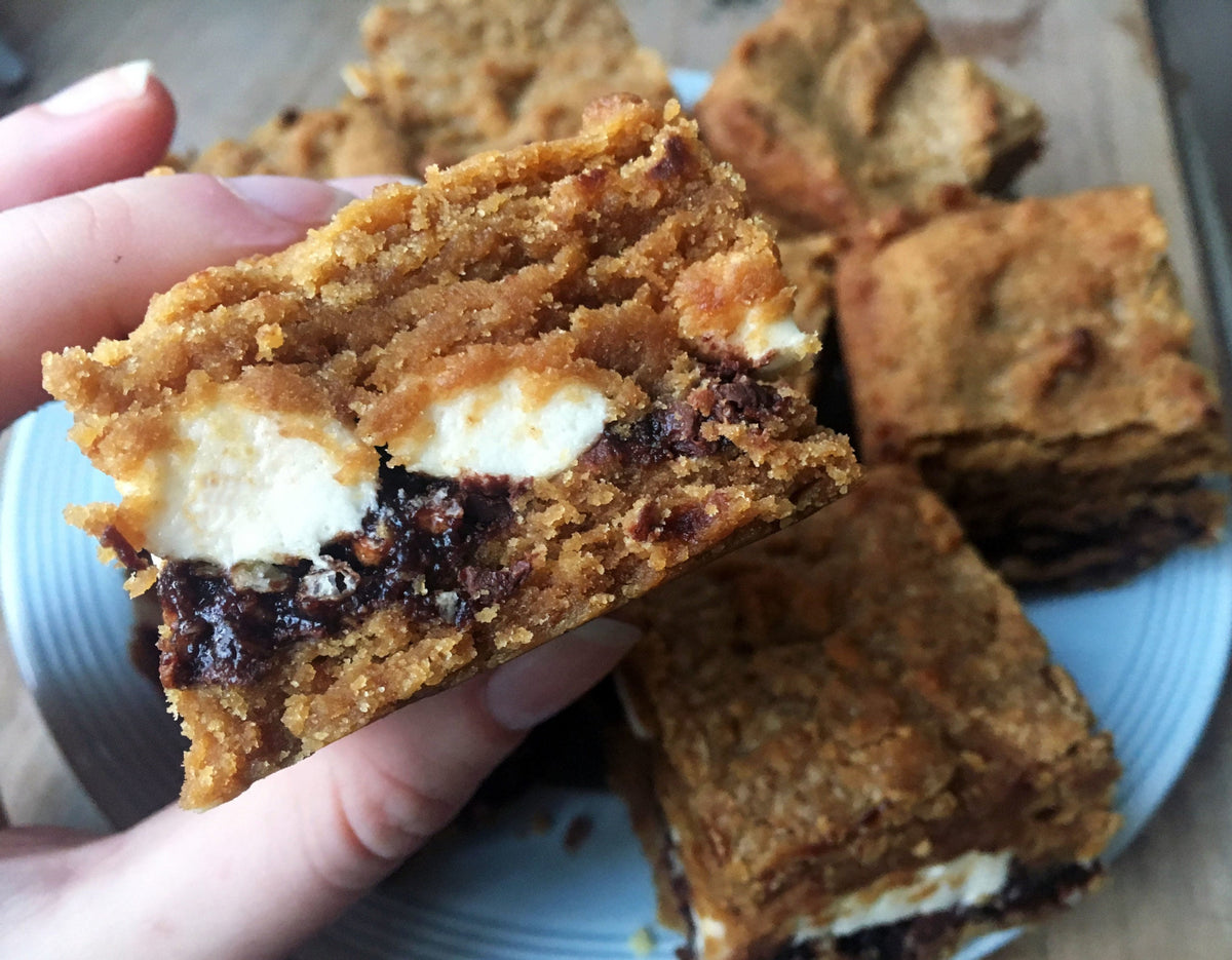 a decadent looking cross-section of a blondie with a gooey chocolate later and a squishy marshmallow layer