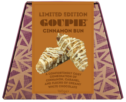 A boxed gourmet chocolate bun from Goupie, featuring a tan and purple geometric patterned box with a central label showing a cinnamon bun drizzled with white chocolate.