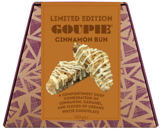 A boxed gourmet chocolate bun from Goupie, featuring a tan and purple geometric patterned box with a central label showing a cinnamon bun drizzled with white chocolate.