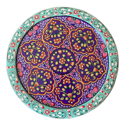 A round decorative gift tin with a colourful floral and paisley pattern