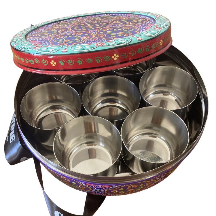 A round decorative gift tin with a colourful floral and paisley pattern, slightly opened to show 7 smaller internal tins