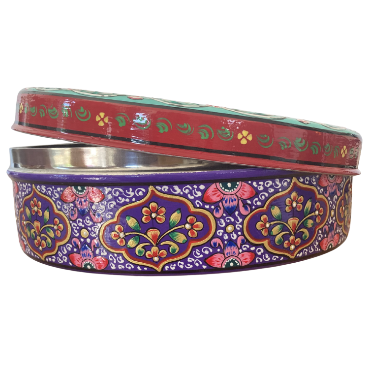 Sideview of a round decorative gift tin with a colourful floral and paisley pattern, slightly opened
